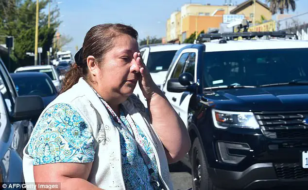 CD Another reacts while crossing the street past police vehicles ou a